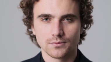 A close-up view of a handsome man is smiling to the camera standing isolated over gray wall in the studio