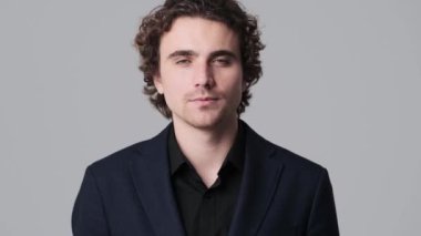 A confident young man is showing ok gesture standing isolated over gray wall in the studio