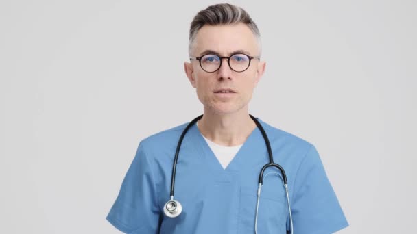Шокований Старший Лікар Медичній Формі Турбується Про Стоїть Ізольовано Сірому — стокове відео