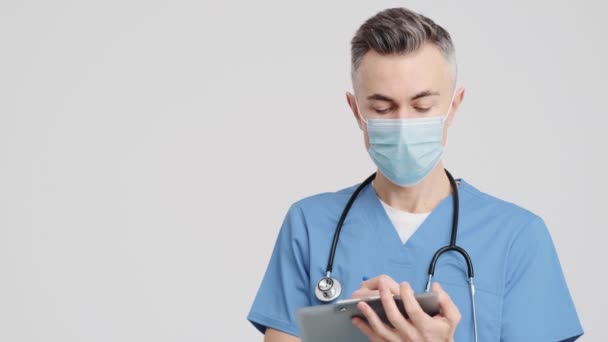 Ένας Σοβαρός Ανώτερος Γιατρός Που Φοράει Ιατρική Στολή Κρατάει Σημειώσεις — Αρχείο Βίντεο
