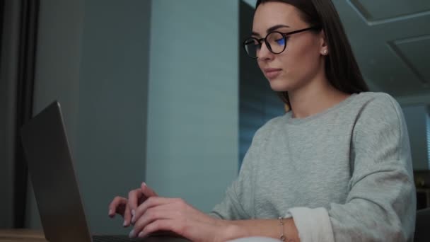 Una Joven Satisfecha Con Gafas Está Usando Computadora Portátil Mientras — Vídeos de Stock
