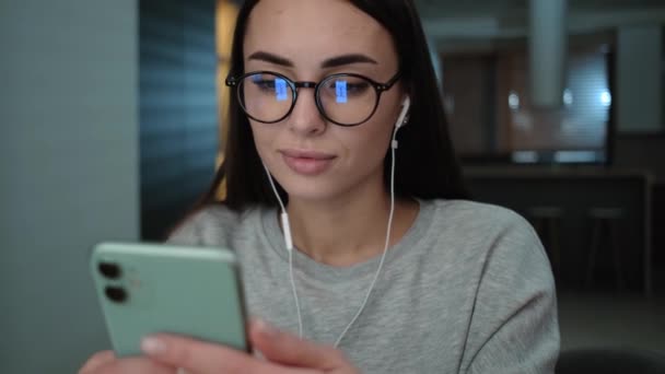 Een Positieve Vrouw Met Een Bril Gebruikt Haar Smartphone Appartementen — Stockvideo