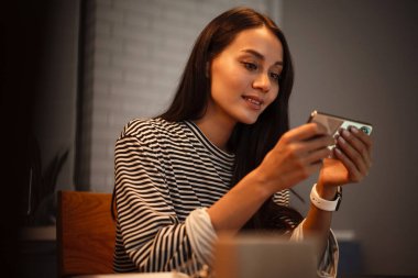 Ev mutfağında cep telefonu kullanan hoş bir kadın.