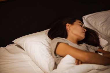 Esmer, beyaz, güzel bir kadın evde uyuyor.