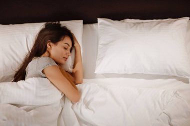 Esmer, beyaz, güzel bir kadın evde uyuyor.