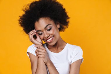 Mutlu Afrikalı Amerikalı kız gülümseyen ve kameraya poz veren sarı arka planda izole edilmiş.
