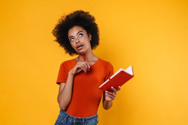 Afrika kökenli Amerikalı bir kızın sarı arka planda izole edilmiş notlar yazdığını düşünüyorum.