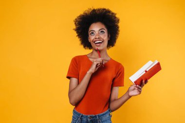 Gülümseyen Afrikalı Amerikalı kız sarı arka planda izole edilmiş notlar yazıyor.