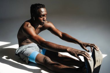 Kendine güvenen Afrikalı sporcu gri arka planda izole edilmiş bir spor minderi üzerinde egzersiz yapıyor.