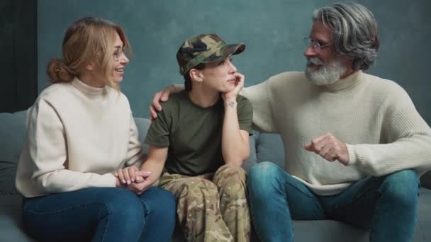 一位身穿军服的快乐的年轻女子正在屋里与她的父母交谈 — 图库视频影像