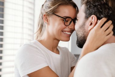 Güzel mutlu beyaz çift içeride gülüyor ve sarılıyor.