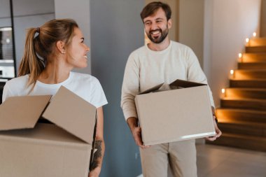Gülümseyen ve yeni dairede karton kutular taşıyan güzel bir çift.