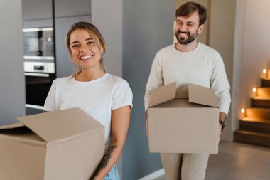 Gülümseyen ve yeni dairede karton kutular taşıyan güzel bir çift.