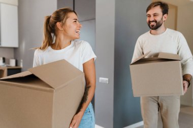 Gülümseyen ve yeni dairede karton kutular taşıyan güzel bir çift.
