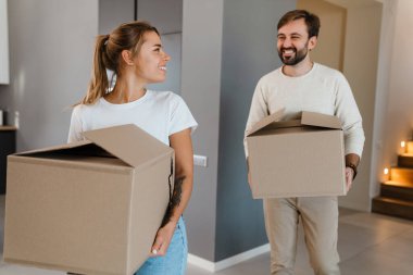 Gülümseyen ve yeni dairede karton kutular taşıyan güzel bir çift.