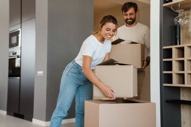 Gülümseyen ve yeni dairede karton kutular taşıyan güzel bir çift.