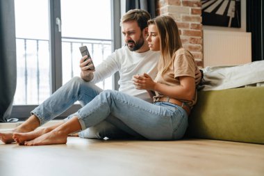 Evde otururken cep telefonuna bakan hoşnutsuz çift