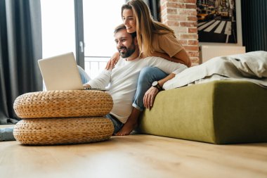 Mutlu çift evde dizüstü bilgisayarla rahatlıyor.