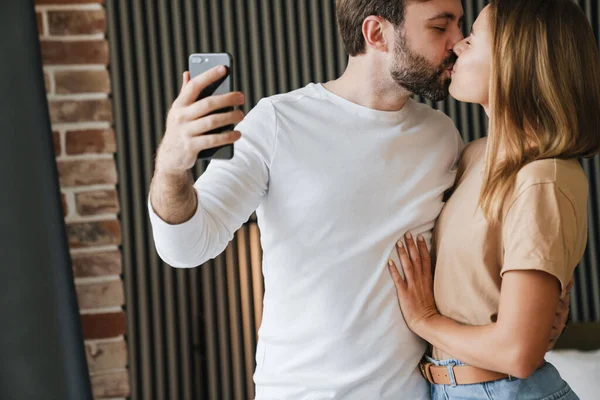 Couple in love enjoying weekend and taking selfies in bedroom