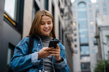 Gülümseyen ve cep telefonu kullanan mutlu bir öğrenci kız.