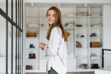 Güzel, neşeli, güzel bir kız. Gülümsüyor ve dolabında poz veriyor.