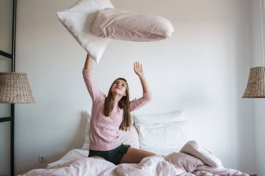 Güzel, heyecanlı, güzel kız evde yastıklarla gülüp eğleniyor.