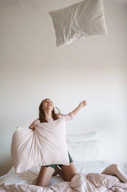 Güzel, heyecanlı, güzel kız evde yastıklarla gülüp eğleniyor.