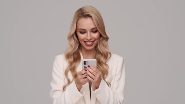 Överraskad Ung Blond Affärskvinna Använder Sin Smartphone Stående Isolerad Över — Stockvideo