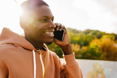 Köprüde cep telefonu kullanan çekici Afrikalı genç bir adam.