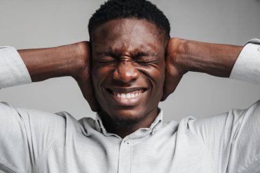 Beyaz gömlekli üzgün Afrikalı adam gri arka planda izole edilmiş baş ağrısından muzdarip.