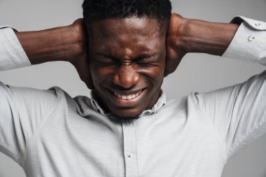 Beyaz gömlekli üzgün Afrikalı adam gri arka planda izole edilmiş baş ağrısından muzdarip.