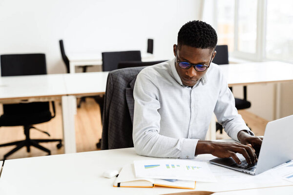 Thoughtful young african american businessman working on laptop computer