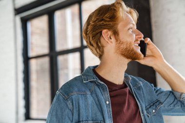 Kapalı alanda gülümseyen ve konuşan mutlu, yakışıklı kızıl adam.
