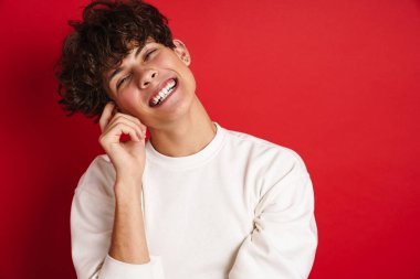 Yakışıklı, güler yüzlü ve kırmızı arka planda izole edilmiş kameraya bakan adam.