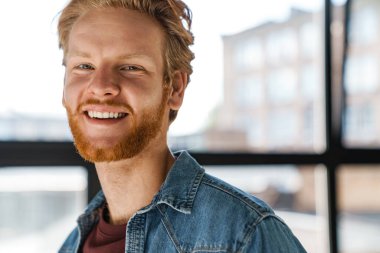 Mutlu yakışıklı kızıl adam gülümsüyor ve kameraya bakıyor.