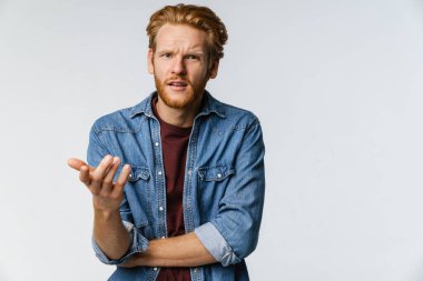 Hoşnut olmayan yakışıklı adam beyaz arka planda izole edilmiş kamerayı işaret ediyor.