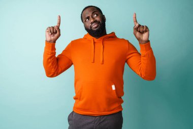 Fotokopi alanını sunan sıradan bir Afrikalı genç adam mavi arka planda izole edilmiş.