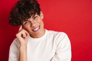 Yakışıklı, güler yüzlü ve kırmızı arka planda izole edilmiş kameraya bakan adam.