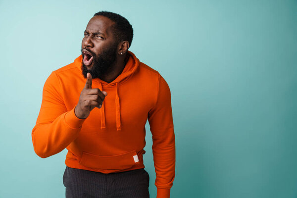 Excited african american man looking and pointing finger at camera isolated over blue background