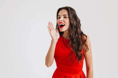 Mutlu, güzel, kırmızı elbise giyen, gülümseyen ve çığlık atan beyaz arka planda yalnız bir kız.