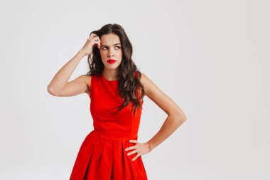 Kafası karışmış güzel esmer kız beyaz arka planda izole bir şekilde düşünüyor ve yukarı bakıyor.