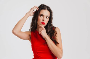 Kafası karışmış, kırmızı elbiseli, beyaz arka planda yalnız bir şekilde düşünen güzel bir kız.