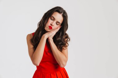 Üzgün, güzel esmer kız beyaz arka planda izole bir şekilde uyku jesti gösteriyor.