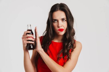 Genç üzgün güzel kadın, gri arka planda izole edilmiş tatlı köpüklü içeceği içmeyi reddediyor.