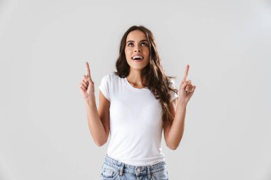 Mutlu güzel kız gülümsüyor ve beyaz arka planda izole bir şekilde parmaklarını yukarı kaldırıyor.