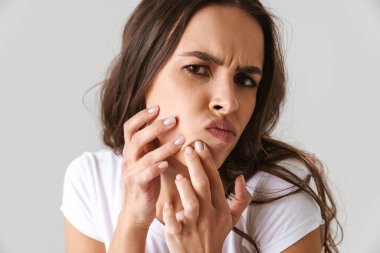 Sivilce çıkaran ve beyaz arka planda izole edilmiş kameraya bakan güzel bir kız.