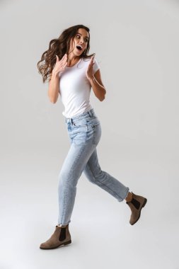 Şok olmuş güzel bir kız beyaz arka planda tek başına yürürken şaşkınlığını ifade ediyor.