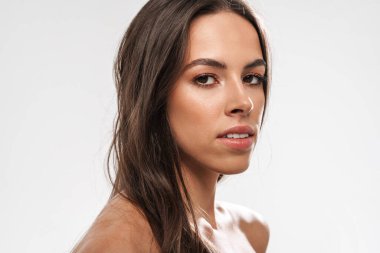 Güzel üstsüz, kendine güveni olan kız beyaz arka planda yalnız başına poz verip kameraya bakıyor.