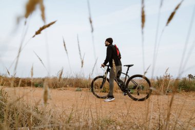 Genç sporcu doğada çalışırken bisiklete biniyor.
