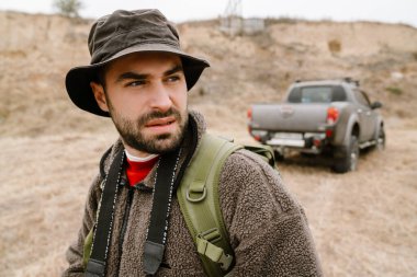 Odaklanmış yakışıklı fotoğrafçı dışarı bakıyor ve yürüyor.